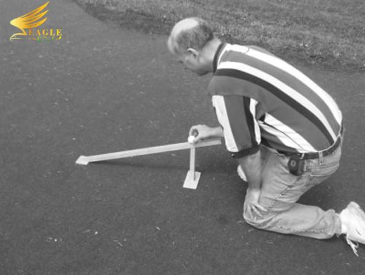 Ảnh người quỳ trên bề mặt putting, đặt bóng lên Stimpmeter